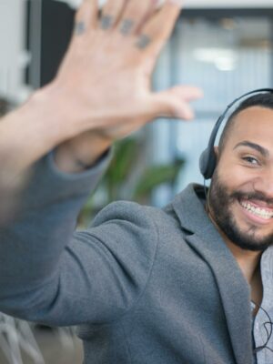 Photo by Kampus Production A cheerful call center agent with a headset gives a high five to a colleague in an office.
